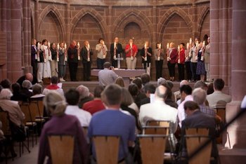 Ökumenische Nacht der Kirchen an Pfingsten Im Altarraum einer gotischen Kirche stehen Vertreter von über zehn Kirchengemeinden und halten große Kerzen mit einem pfingstlichen Motiv in ihren Händen